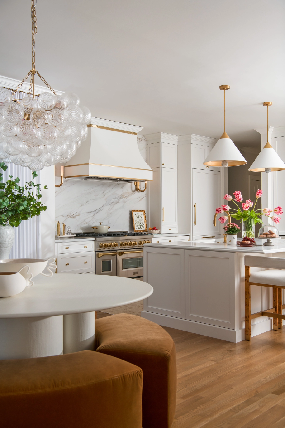 Breakfast nook with bubble glass chandelier, round white table, and velvet seating overlooking the kitchen