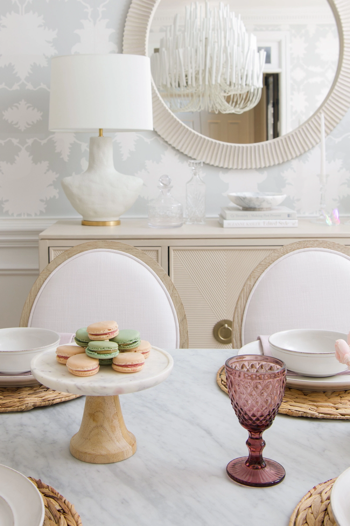 Close-up of pastel macarons on a marble pedestal stand with rose goblets on the dining table