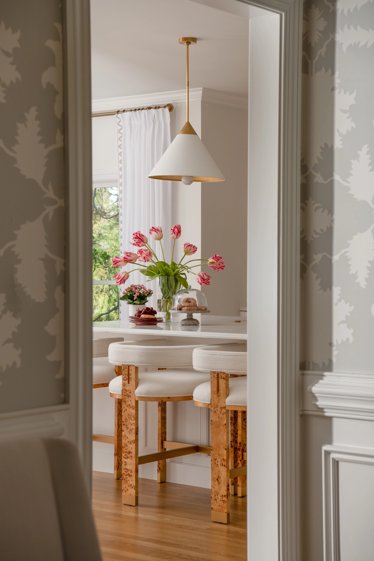 Hallway view into the kitchen through wallpapered corridor with pendant light and bar stools