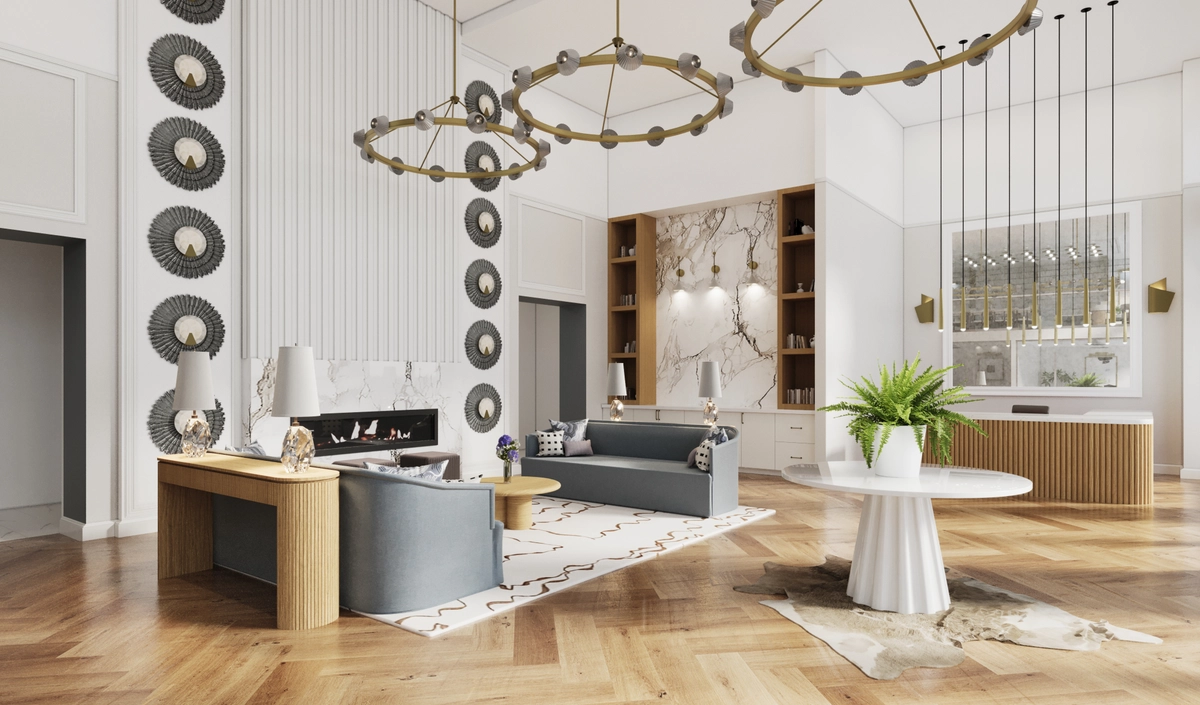 Grand double-height lobby with herringbone hardwood floors, circular brass chandeliers, a linear fireplace flanked by decorative metal disc wall art, gray upholstered sofas, and a built-in bar area with pendant lighting