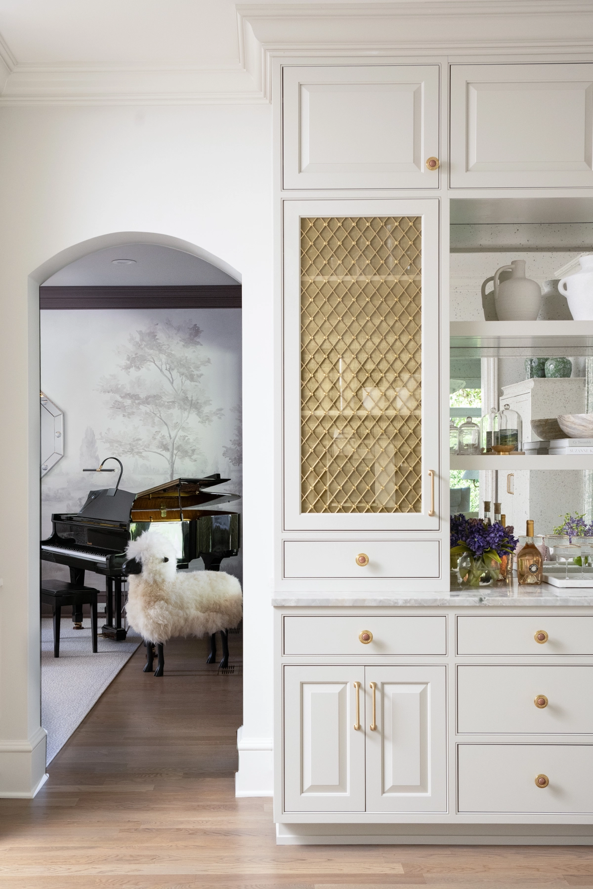 Arched alcove featuring a built-in bar cabinet with elegant shelving and warm accent lighting in a refined entertaining space
