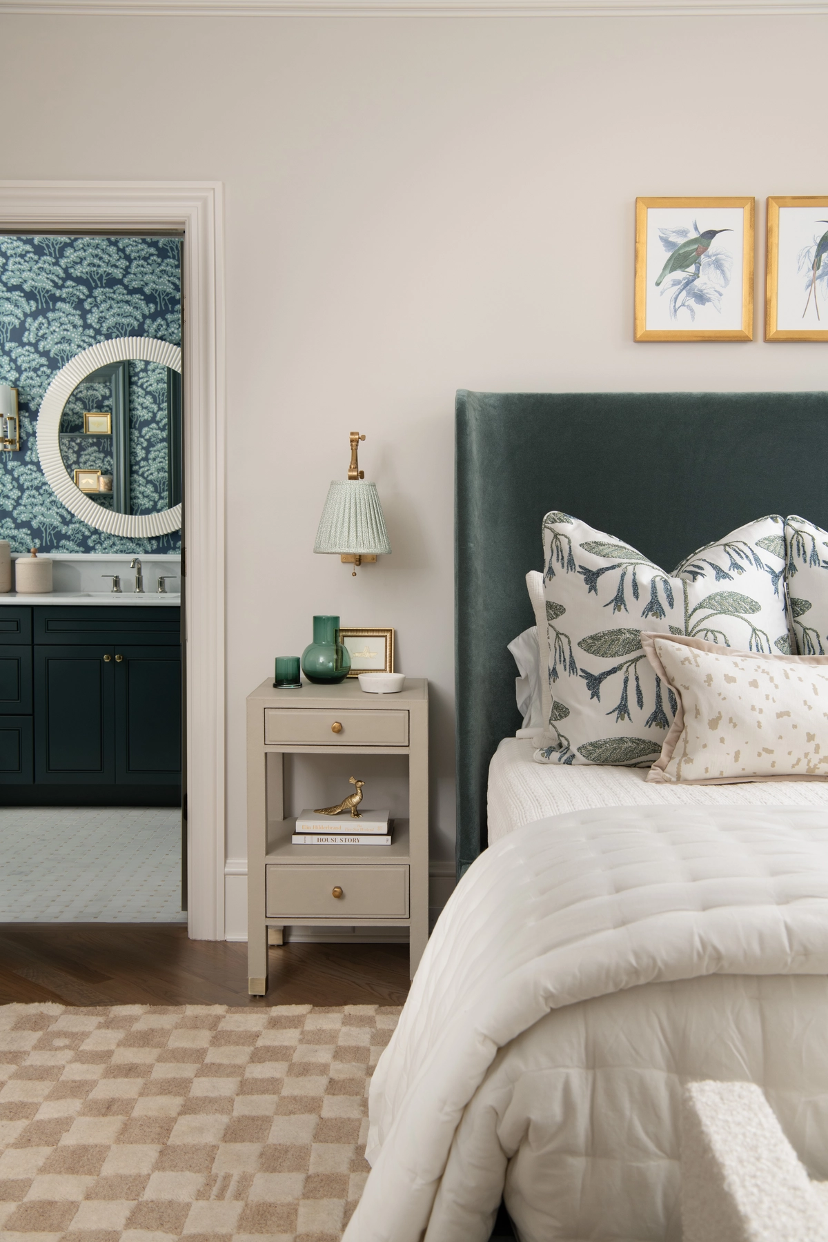 Bedroom with a deep teal velvet headboard, botanical patterned pillows, and a doorway revealing a teal ensuite bathroom with tree wallpaper